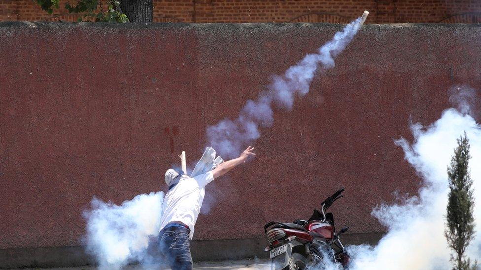 Kashmiri student throws back a tear smoke shell at Indian police personnel during clashes in Srinagar, the summer capital of Indian Kashmir, 14 May 2019.