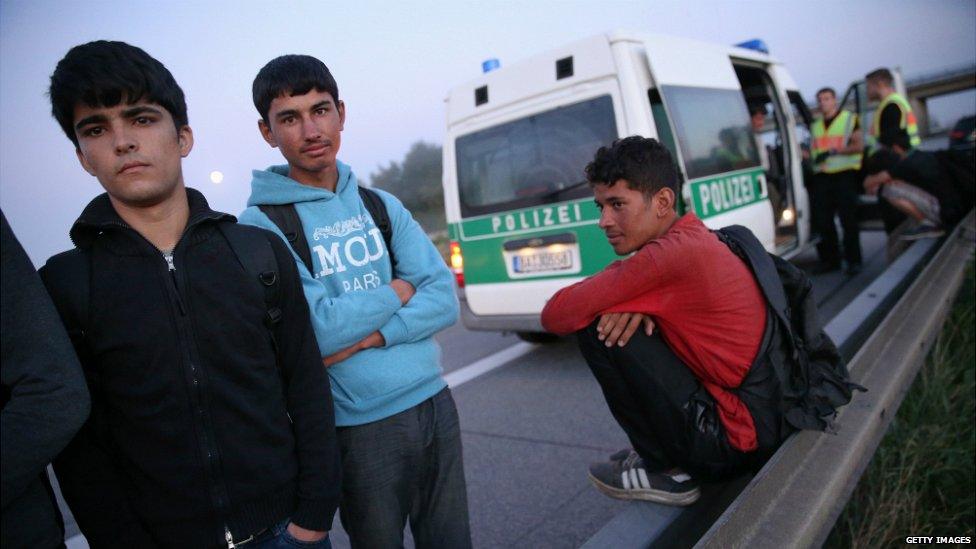 Police prepare to load a group of Afghan migrants into a van after they were found walking along a main road - 30 August 2015