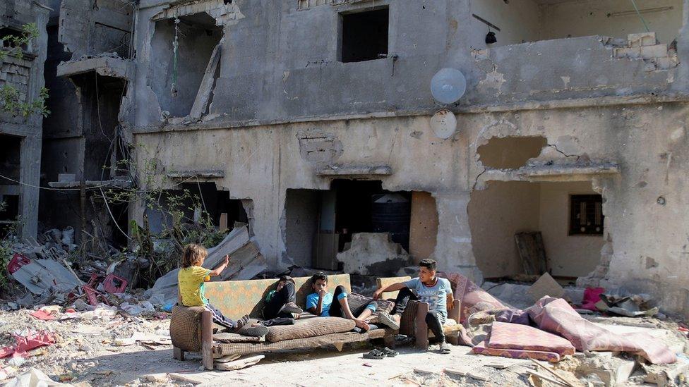 Palestinian children sit near the rubble of houses in Gaza that were destroyed in Israeli air strikes (9 June 2021)