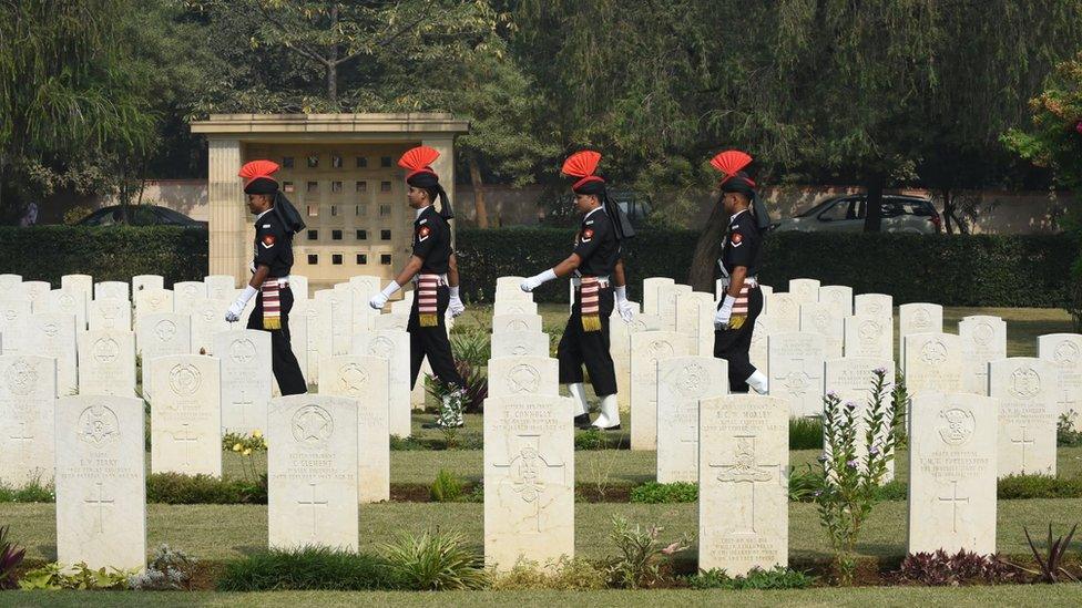 Indian Army soldiers walk among tombstones at Delhi War Cemetery in New Delhi on November 9, 2014, during a Remembrance Sunday Ceremony.