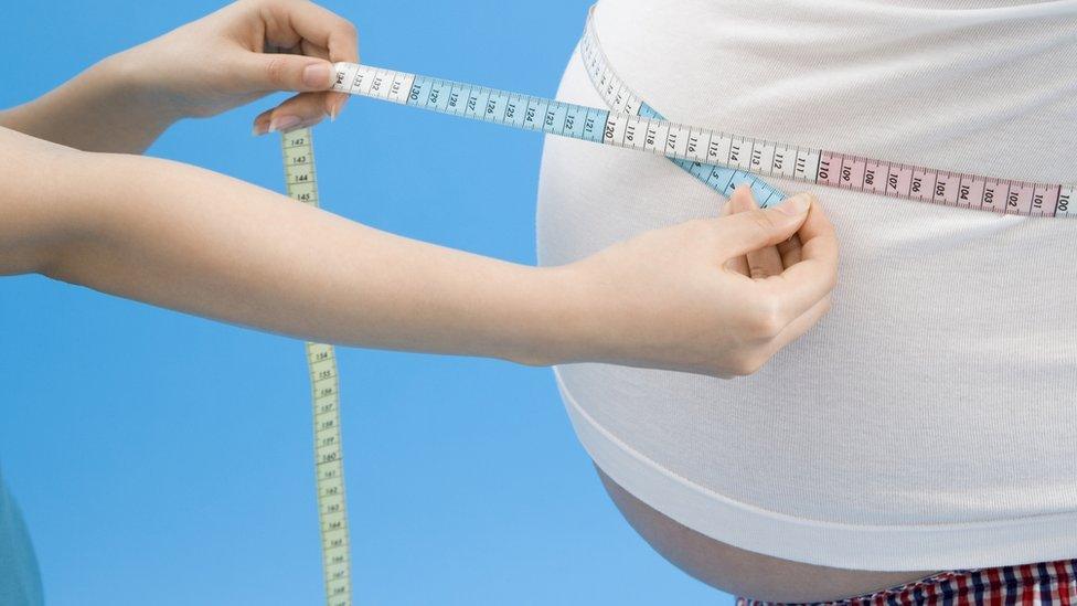 Obese man having his stomach measured