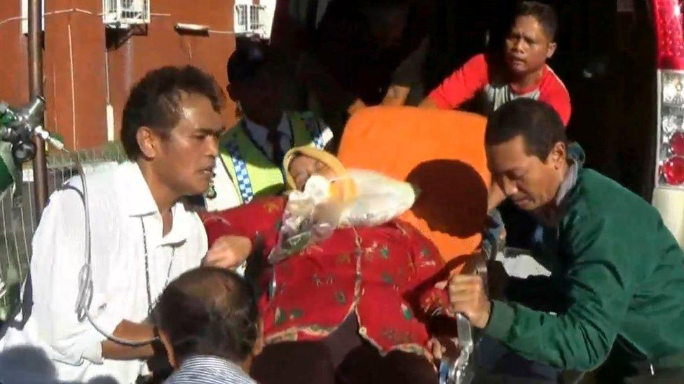 A woman being lifted into an ambulance by paramedics at the airport, on 4 May