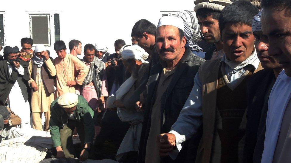 Men gather around the bodies of civilians killed by Islamic State militants in Ghor province on 26 October 2016