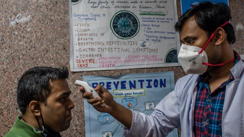 A doctor checks another man's temperature