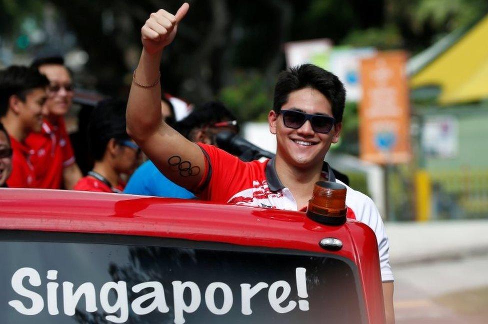 Singapore's Olympic gold medallist swimmer Joseph Schooling gestures during a victory parade on an open top bus in Singapore August 18, 2016.