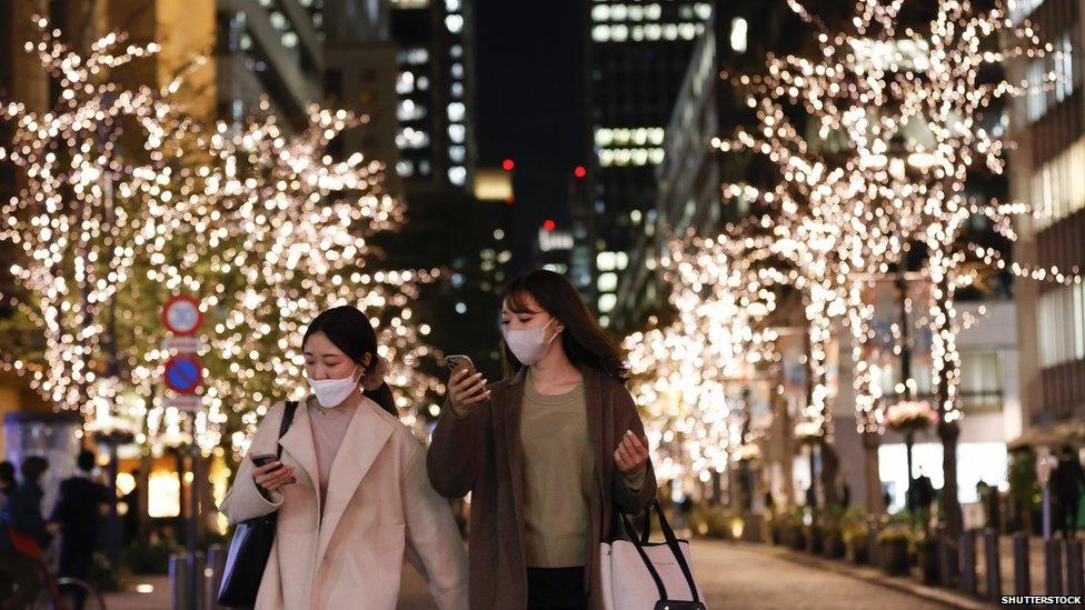 Two shoppers in Tokyo with led trees behind them