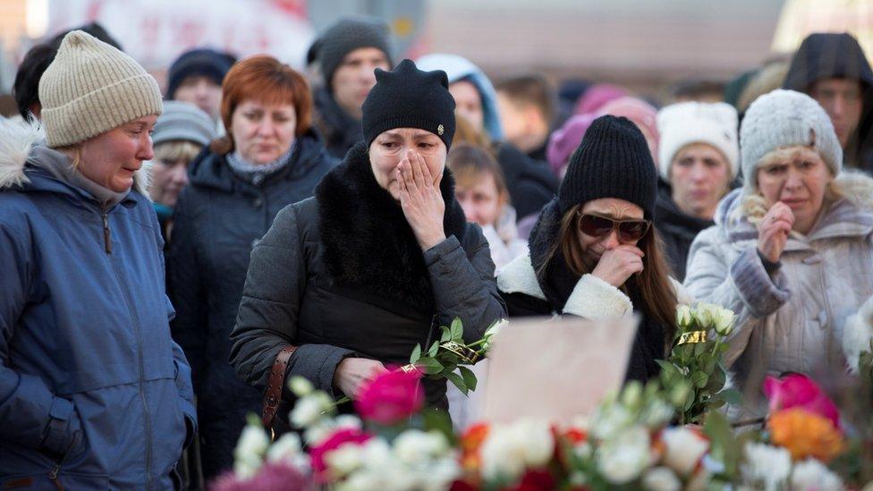 People mourn the victims of a shopping mall fire at a makeshift memorial in the Siberian city of Kemerovo, 26 March