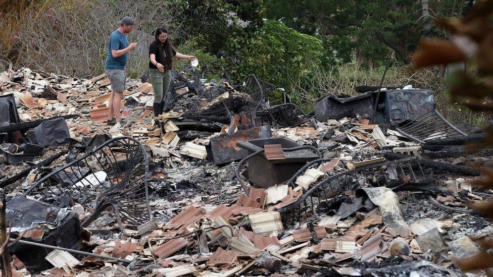 Residents look through the charred remains of a home