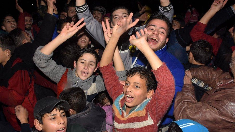 Syrians celebrate on December 12, 2016 in the government-held Mogambo neighbourhood of the northern Syrian city of Aleppo, after rebel fighters retreated into a small pocket of their former bastion in the face of new army advances.