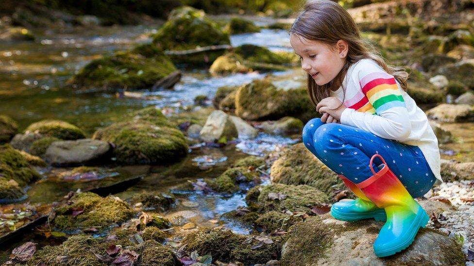 Girl sitting near shallow river