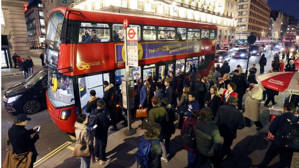 Commuters queue for a bus in Piccadilly, central London