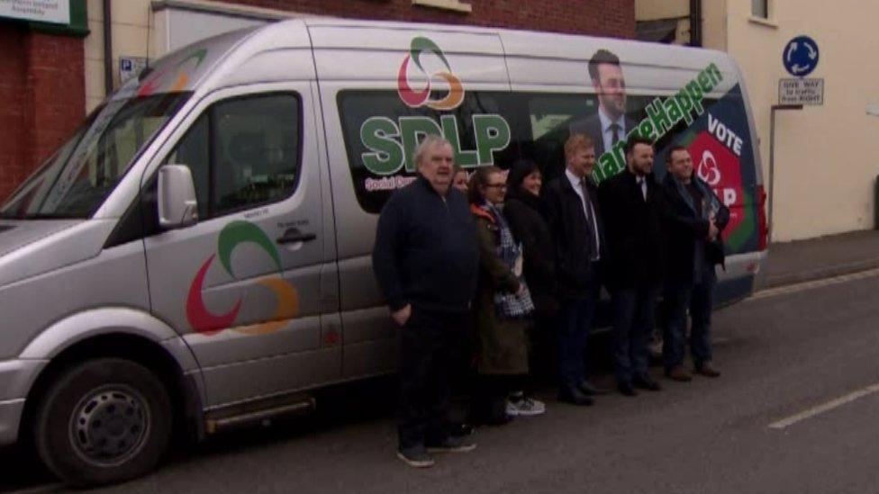 SDLP members stand beside the party's battle-bus