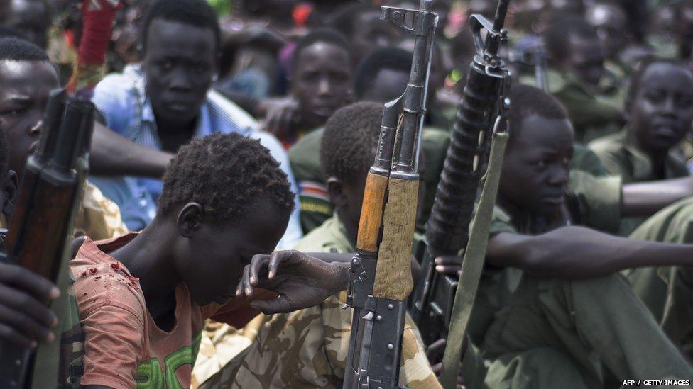 Young boys, children soldiers sit on with their rifles at a ceremony of the child soldiers disarmament, demobilisation and reintegration in Pibor overseen by UNICEF and partners 10 February 2015