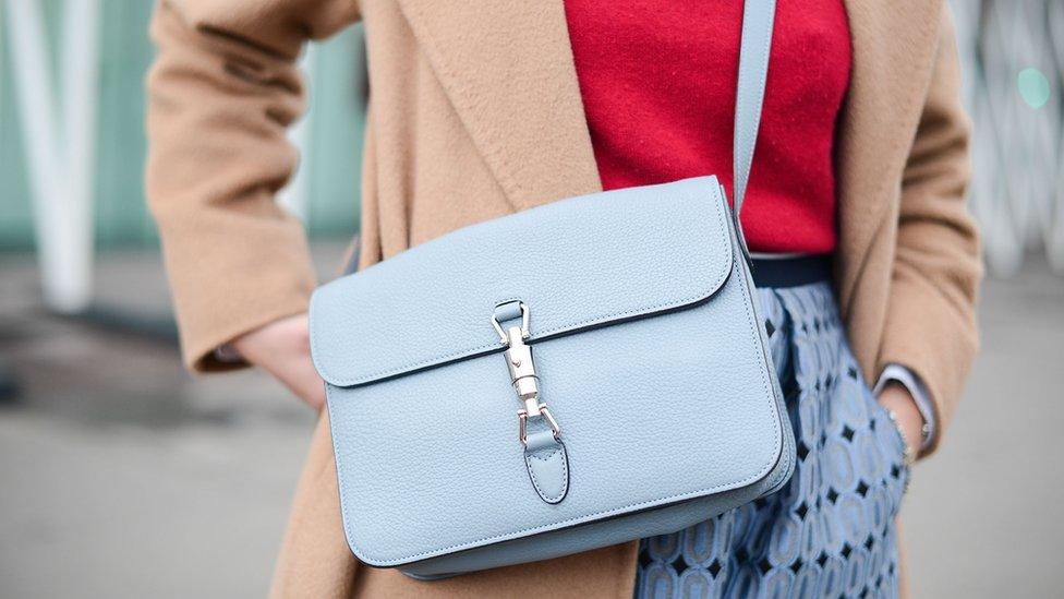 A woman wearing a handbag with a long strap across her should and body meaning her hands are free