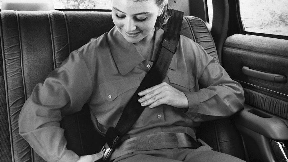 A woman putting on a seat belt