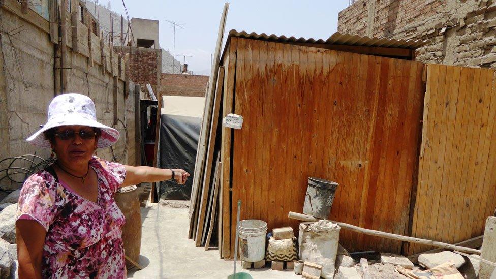 Cristina Inga shows what is left of her house where she lives where she lives with her husband and two children