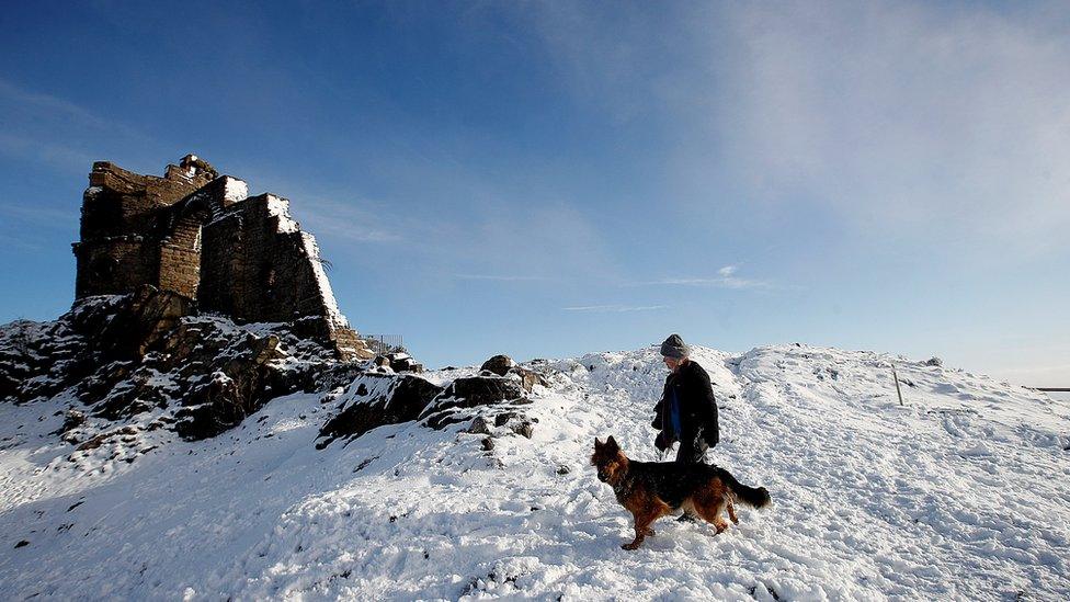 A woman walks her dog at Mow Cop Folly, Cheshire