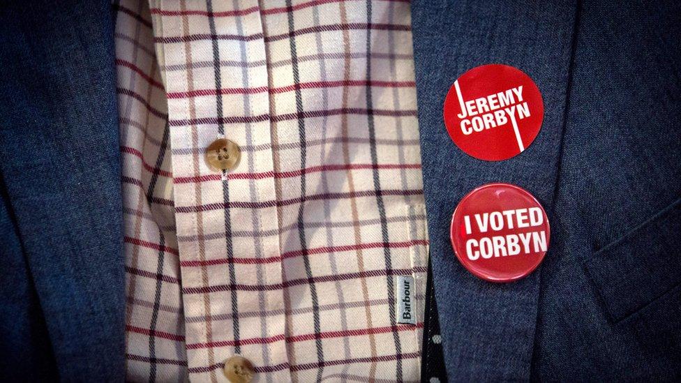 A supporter of Jeremy Corbyn wears badges on a jacket