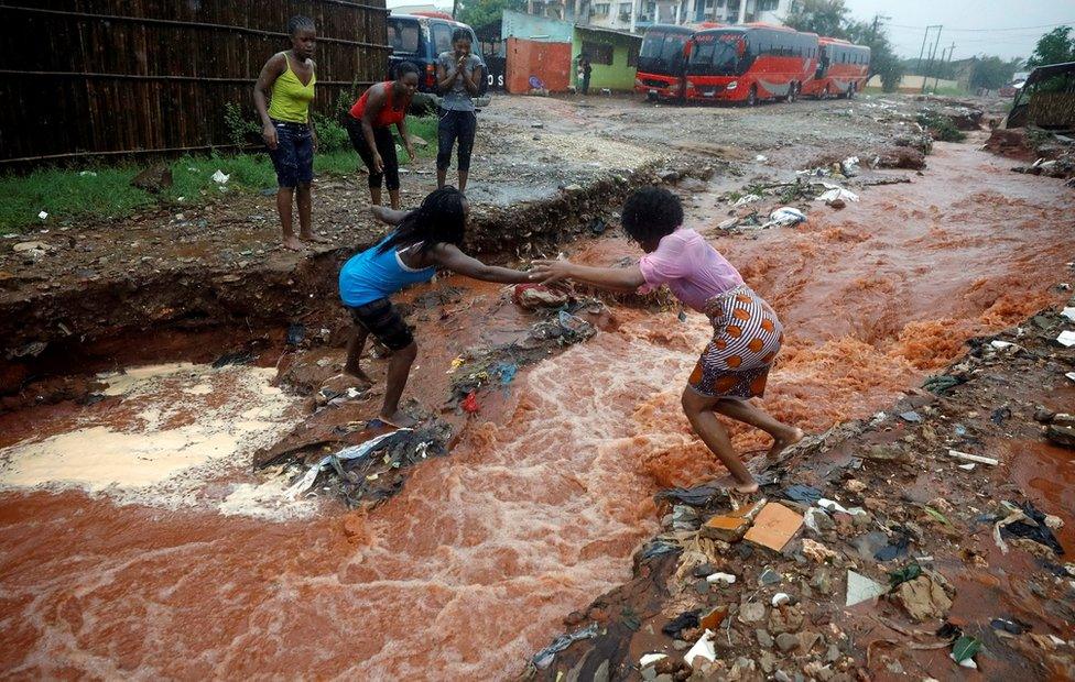 A woman crosses a flooded street in the aftermath of Cyclone Kenneth in Pemba, Mozambique