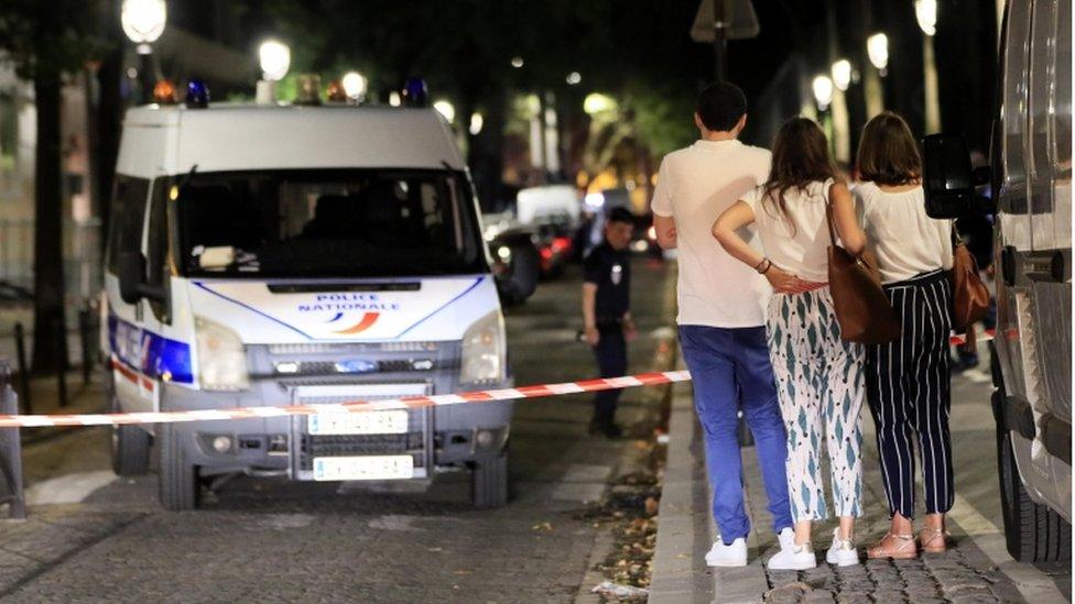 Passers-by look at police at the scene of Paris knife attacks