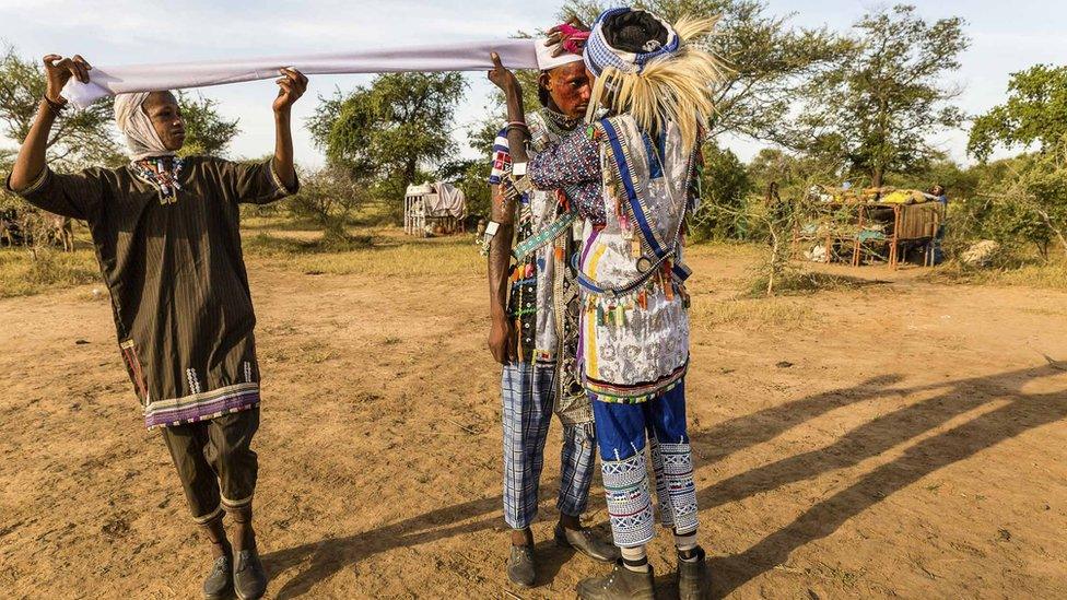 Men help each other get ready for the festival