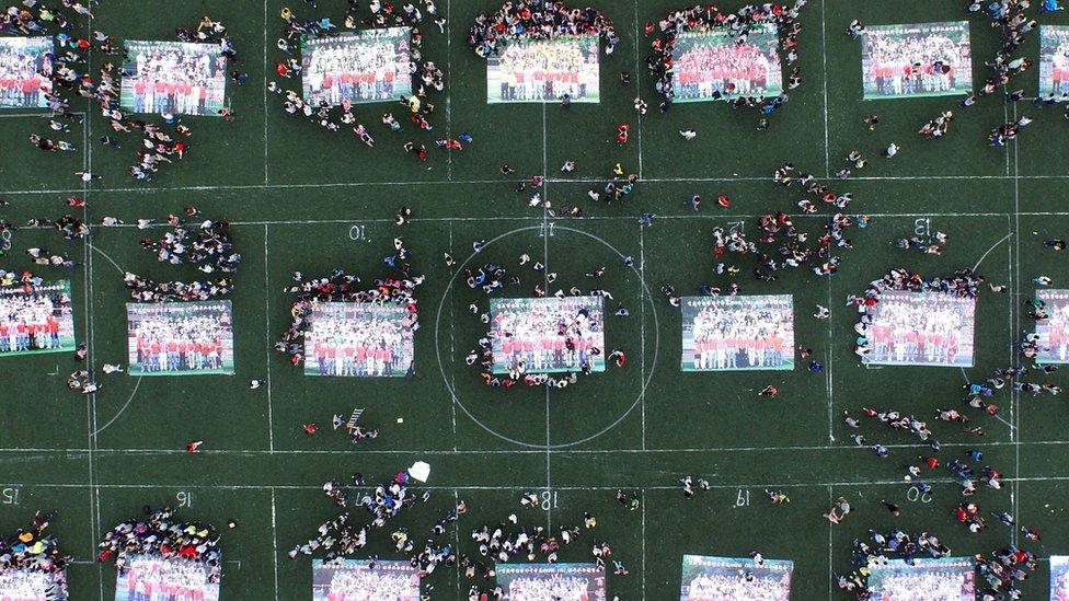 This picture taken on June 8, 2015 shows high school graduates putting together giant jigsaw puzzles made from their graduation photos on the playground after sitting the 2015 national college entrance examination