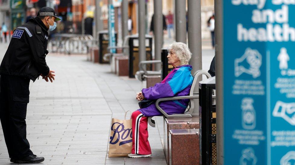 Police officer talking to an elderly woman sat on a bench in Leicester