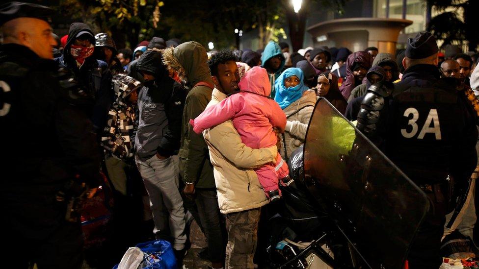 Migrants wait before entering buses