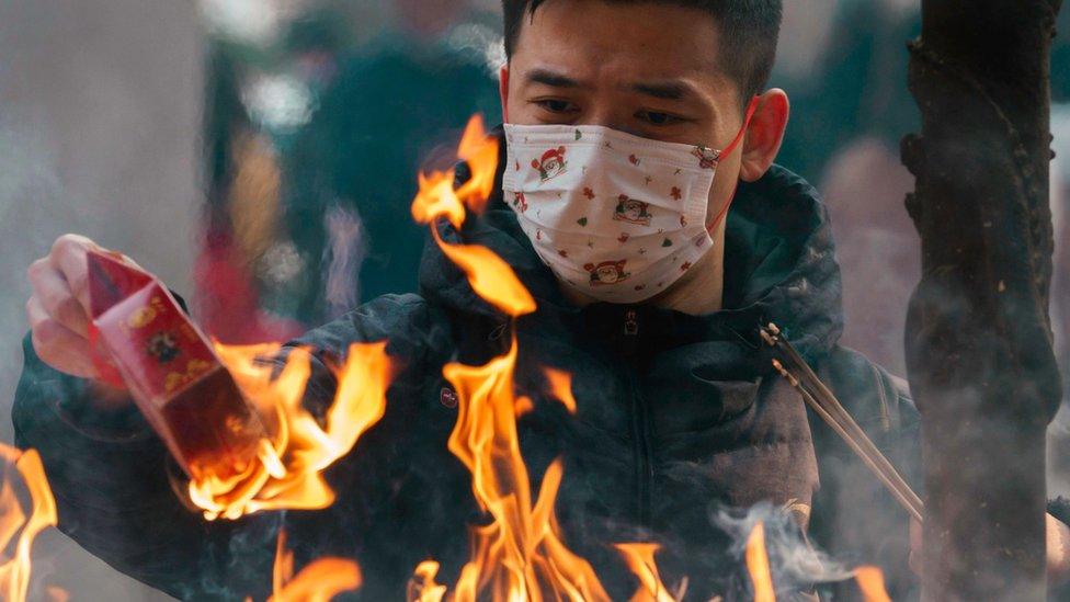 A man burns incense paper and sticks while praying in Jing'an Buddhist Temple for good luck at the beginning of the new year, in Shanghai, China