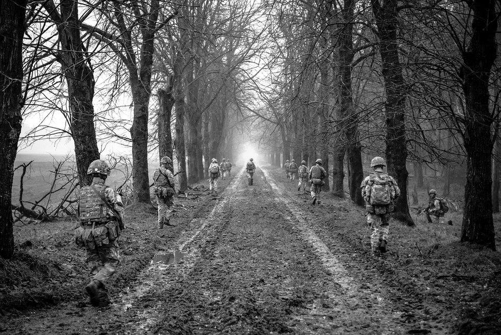 Black and white image of soldiers walking among trees