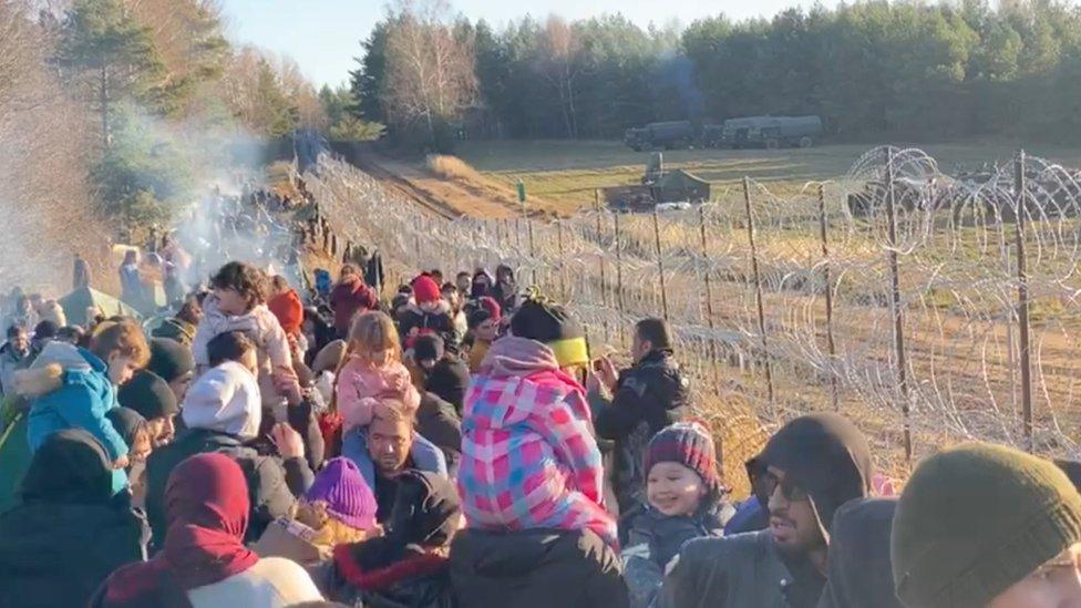 Migrants gather near a barbed wire fence on the Poland - Belarus border in Grodno District, Belarus