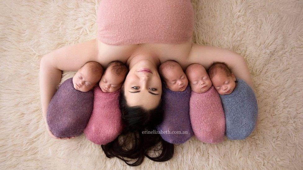 Kim Tucci lies on a rug with her quintuplets