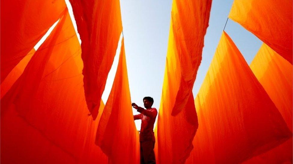 A worker dries fabrics after applying color at a dye factory in Narayanganj, Bangladesh, January 13, 2021.