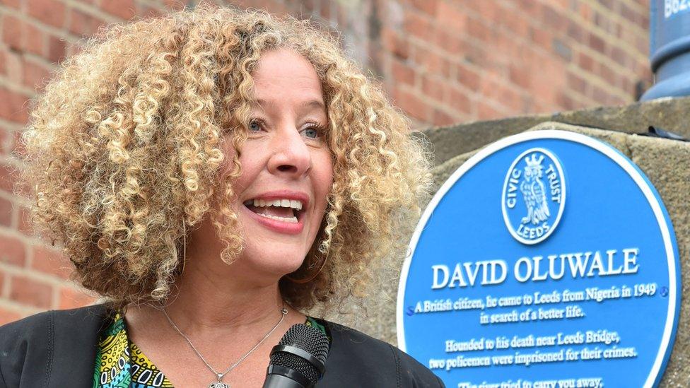 Emily Zobel Marshall talking into a mic in front of the David Oluwale blue plaque