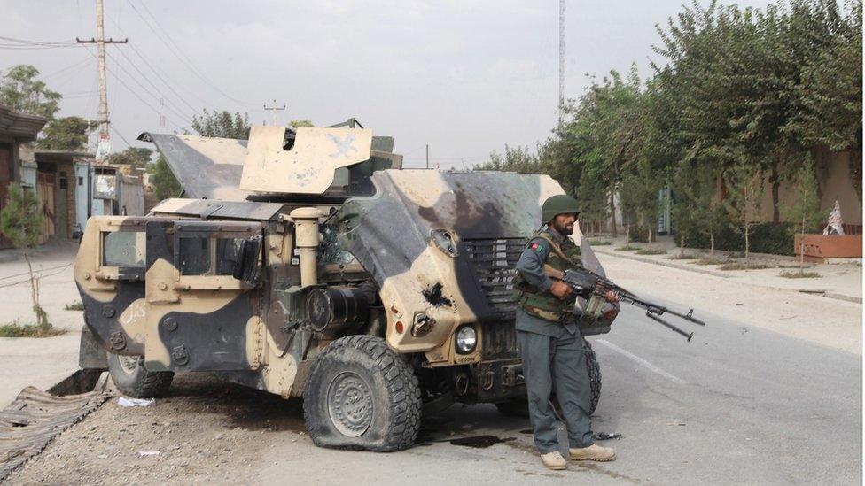 A member of the Afghan security forces stands near an armoured military vehicle in Kunduz, Afghanistan (3 October 2015)