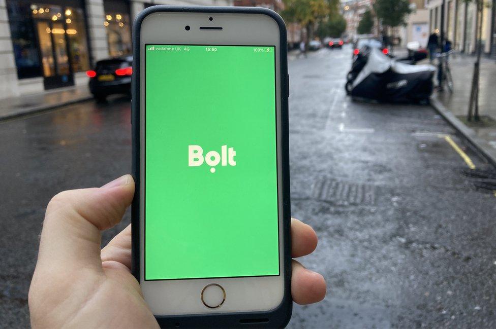 Bolt app on a mobile phone in foreground, car in background