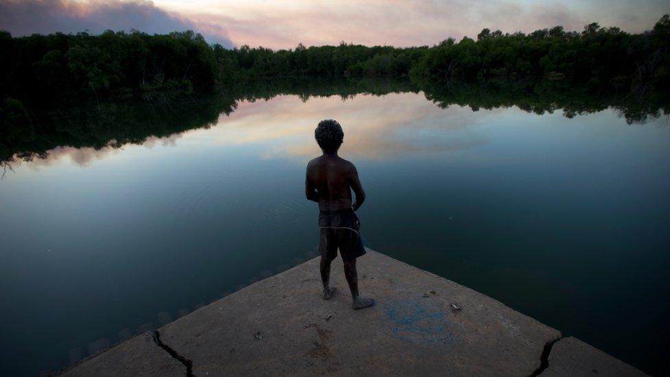 Man stands looking out to lake