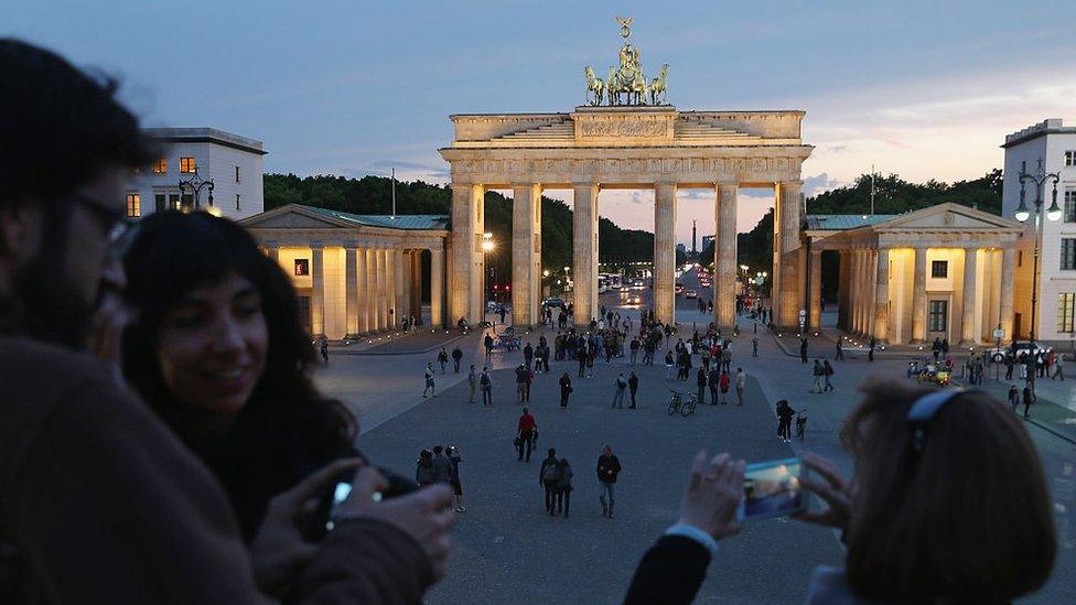 Visitors photograph Pariser Platz square and the Brandenburg Gate from atop a temporary viewing platform on May 19, 2015 in Berlin