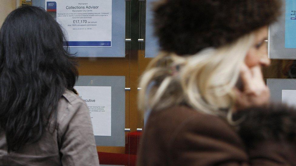 A woman looks at job advertisements in the window of a recruitment agency in Manchester