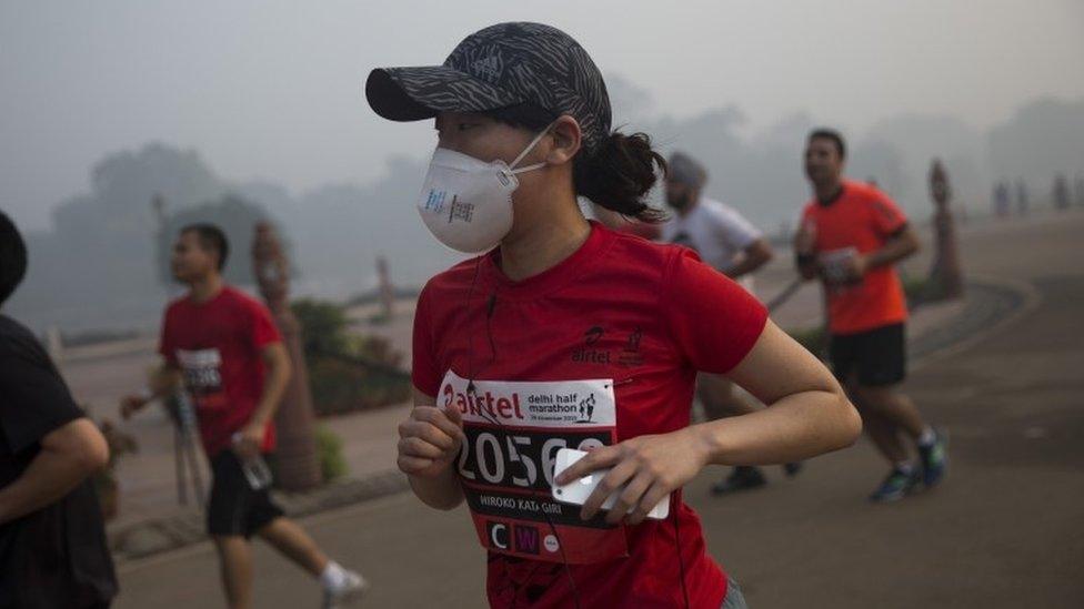 A participant wears a mask as she runs during Delhi Half Marathon in New Delhi, India, Sunday, Nov. 29, 2015