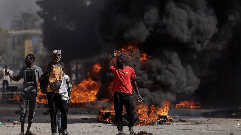 Protesters stand in front of burning barricades in Dakar, Senegal