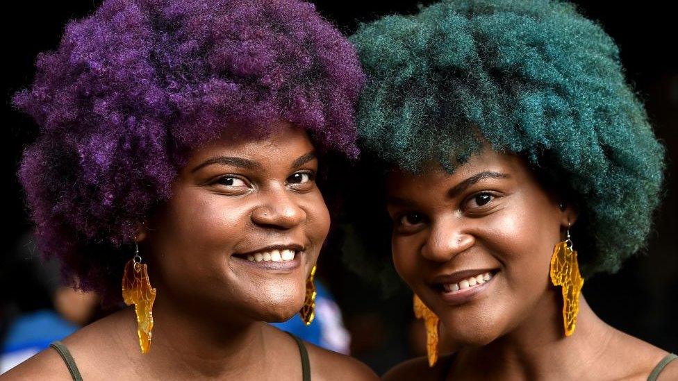 Two women with brightly coloured Afro hair