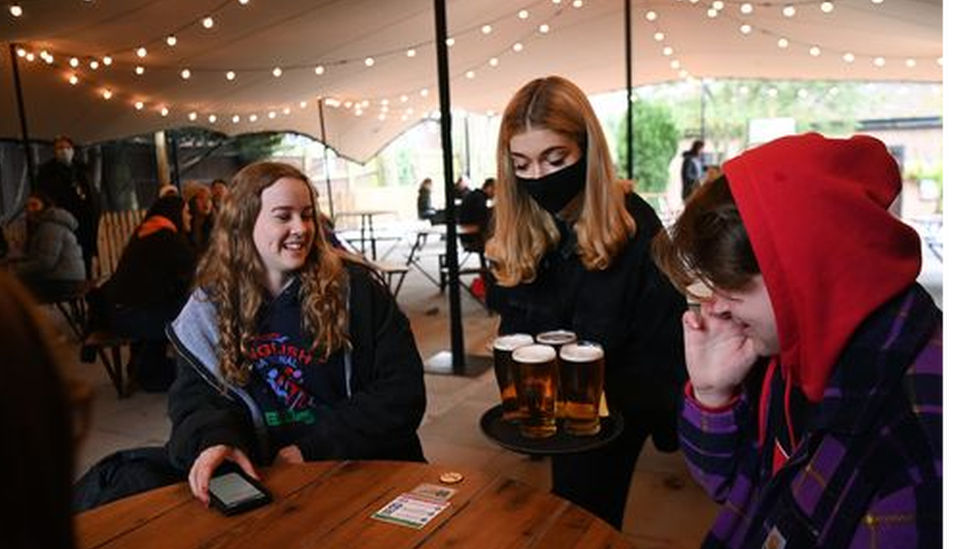 A group being served pints of beer in a marquee