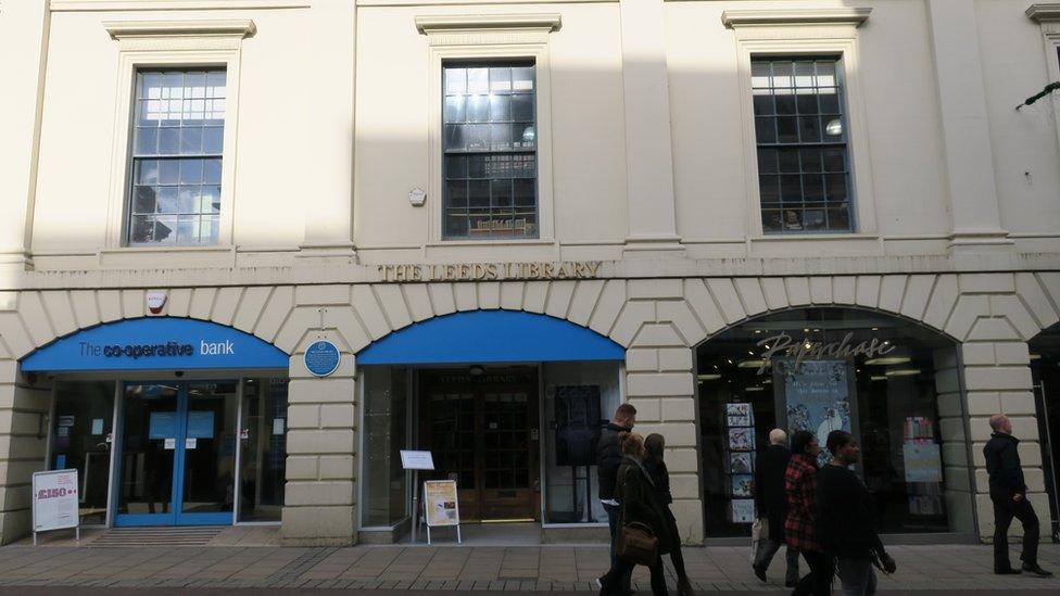 The set-back doorway of the Leeds Library among other shops on Commercial Street