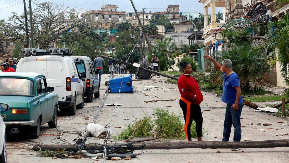 Neighbours in Havana talk with debris strewn in streets around them