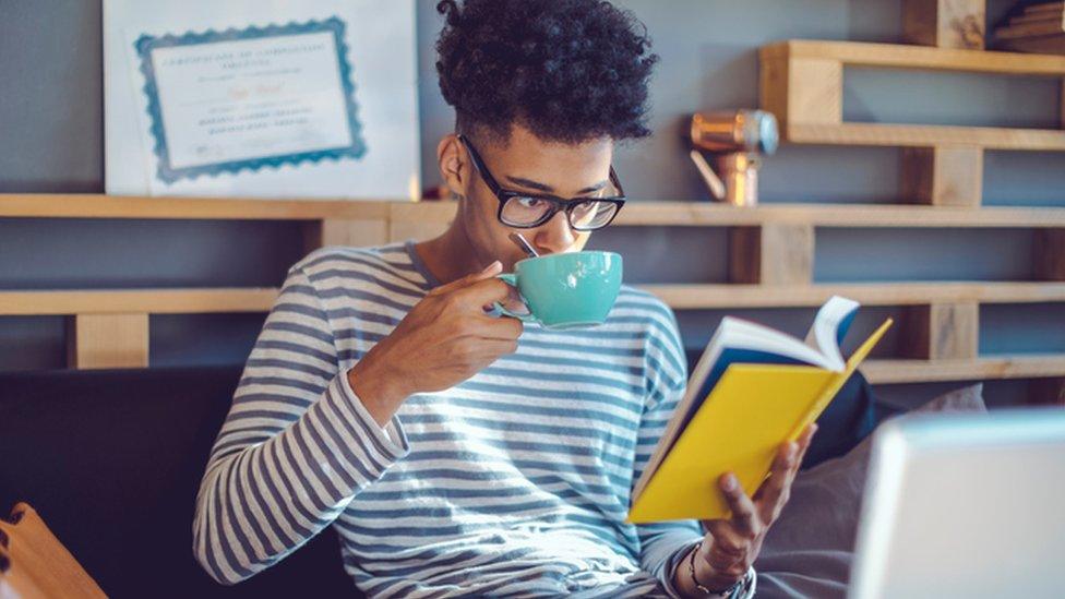 Student reads and drinks cup of tea