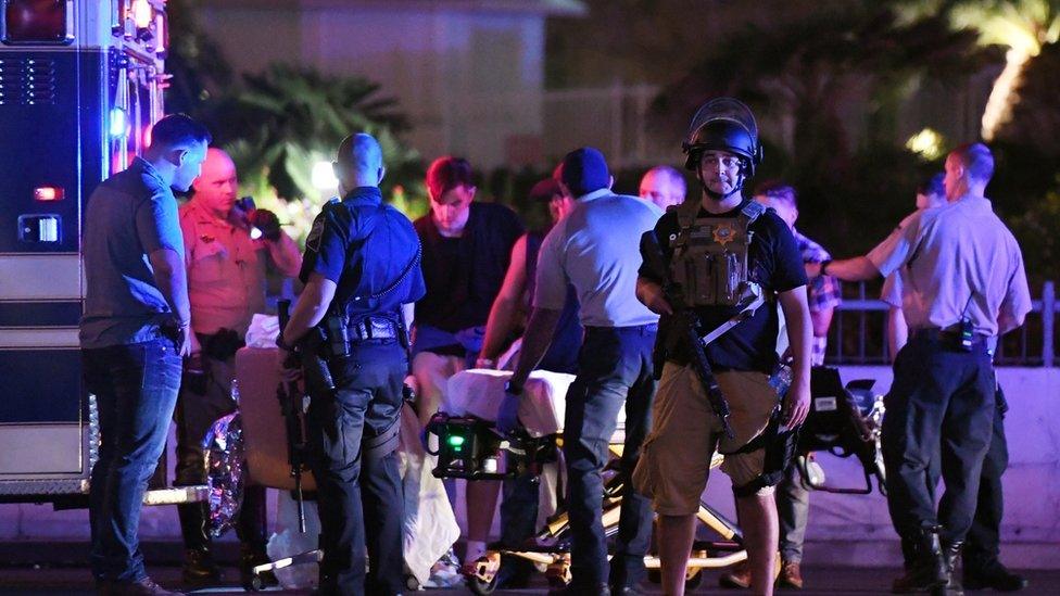 Police officers stand guard as medical staff treat a patient after the mass shooting