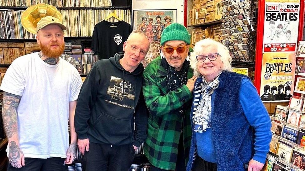 Elvis Costello poses with shop owners