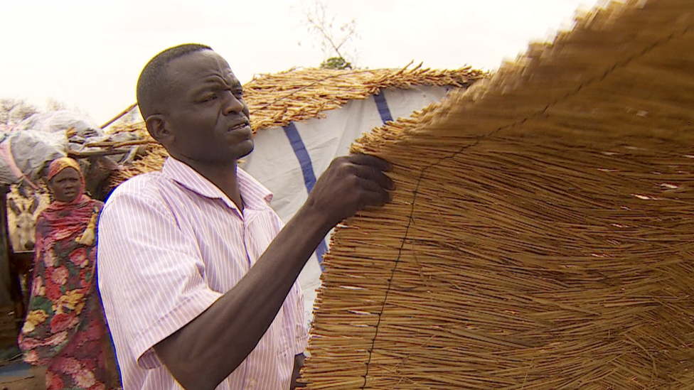 Khamis Mohamed Ishag Osman holds some thatching for a roof