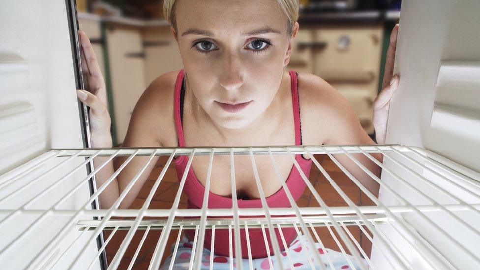 Woman staring into empty fridge